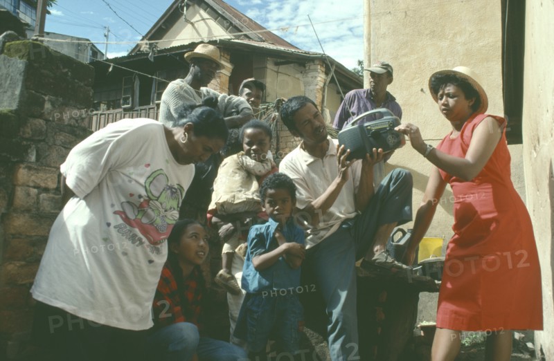 MADAGASCAR, Antananarivo, Group listening to wind up radio.