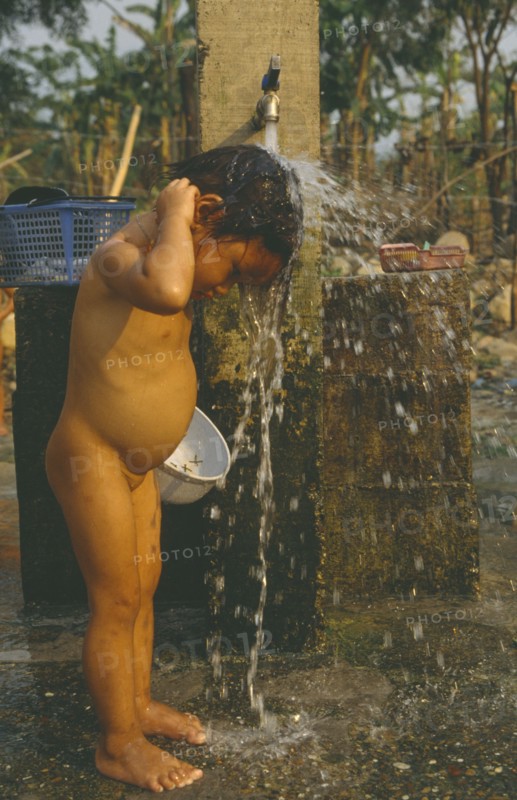 LAOS, Hygiene, Washing, Young Hmong girl washing under stand pipe in Hmong returnee villages for ex-refugees from Thailand.