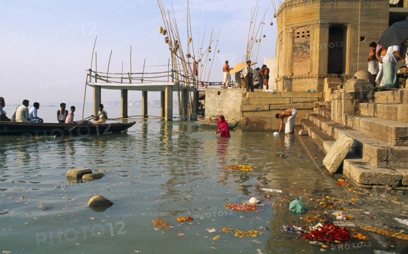 INDIA, Uttar Pradesh, Varanasi, Scum and remnants of flower offerings float around the steps of the ghats on the River Ganges.