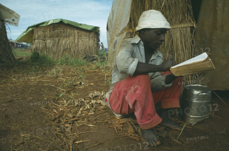 TANZANIA, Heru Oshiuga Camp, Burundian Hutu refugee reading the Bible in refugee camp.