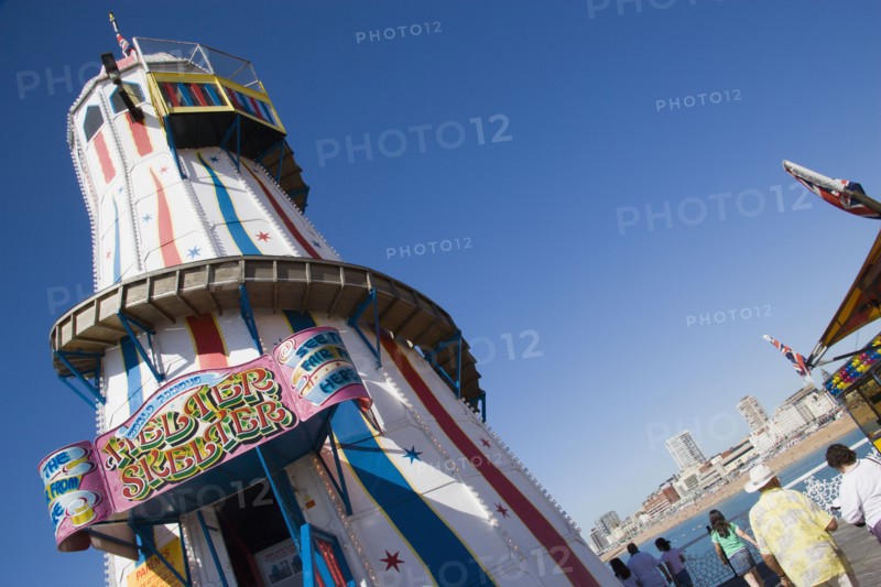 ENGLAND, East Sussex, Brighton, The Helter Skelter ride on Brighton Pier with tourists walking past and the city in the distance