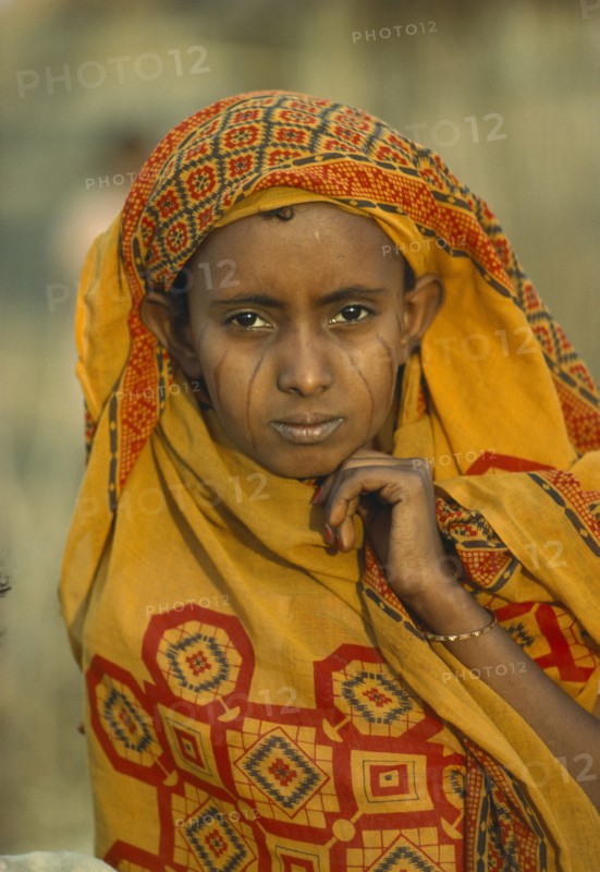 SUDAN, Tribal People, Portrait of Eritrean refugee woman with facial scarification and wearing block printed ochre coloured head covering.