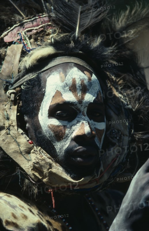 KENYA, Tribal People, Portrait of Kikuyu man with painted face and wearing fur and feather head dress.