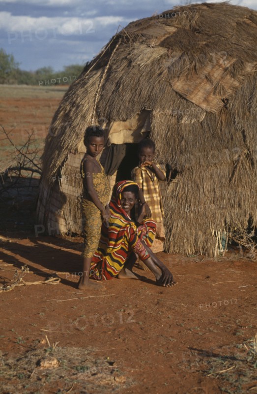 SOMALIA, Gedo, Woman and her two daughters outside their hut.
