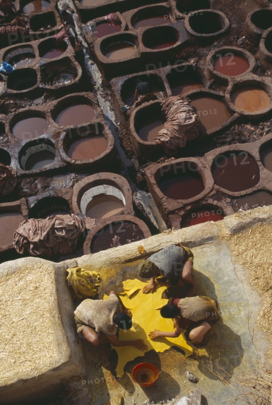 MOROCCO, Fes, Chouwara Tanneries.  Men working at the tanner’s pits with coloured dyes.