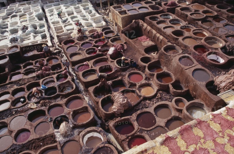 MOROCCO, Fes, Chouwara Tanneries.  Elevated view over men working in the tanner’s pits.