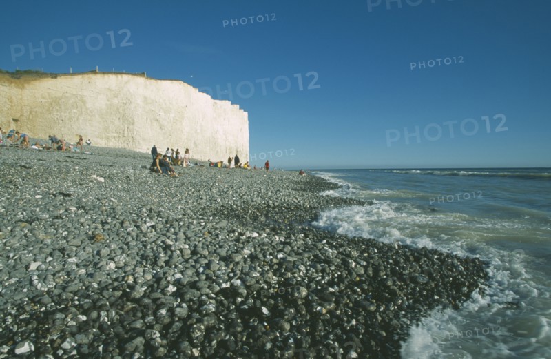 ENGLAND, East Sussex, Birling Gap, Occupied peeble beach with waves lapping and section of cliff face.