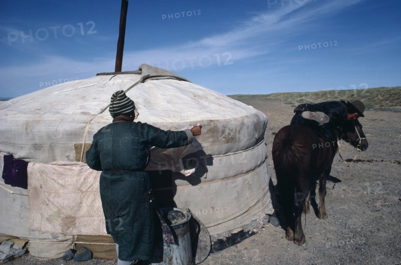 MONGOLIA, Gobi Desert , Herder mounting horse outside Yurt in the southern Gobi.