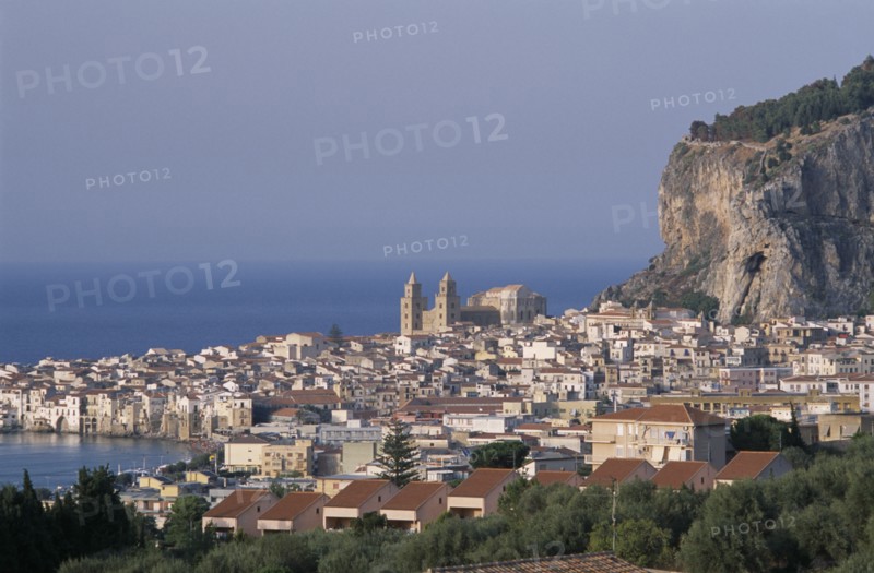 ITALY, Sicily, Palermo, Cefalu. Elevated view over coastal town rooftops and hills towards the sea