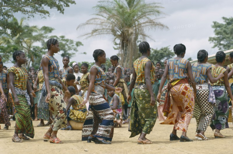 CONGO, Kimpese, Female dancers wearing colourful textiles at festival and watching crowd behind.