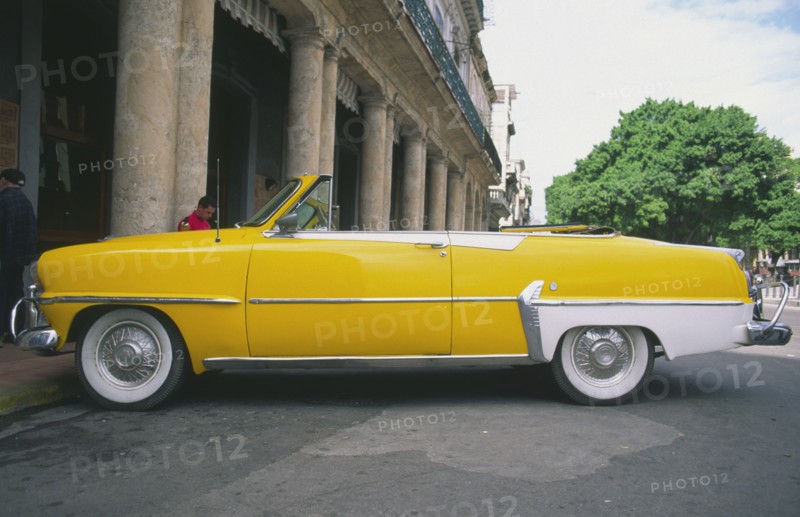 CUBA, Havana, "A classic yellow US 1950s car, parked on the Malecon."