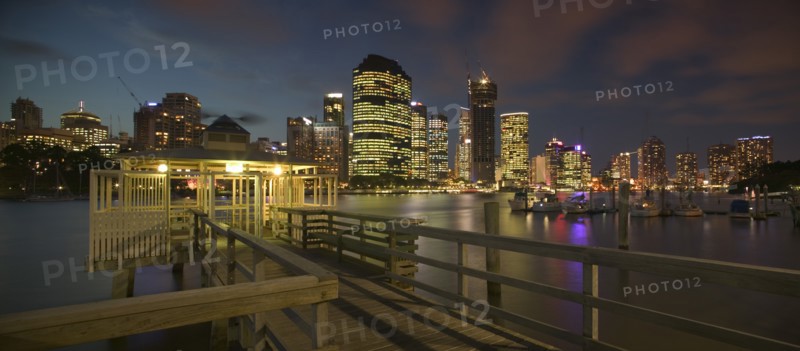 AUSTRALIA, Queensland, Brisbane, "View from a pier, of the CBD across the Brisbane River at dusk with boats on one side."