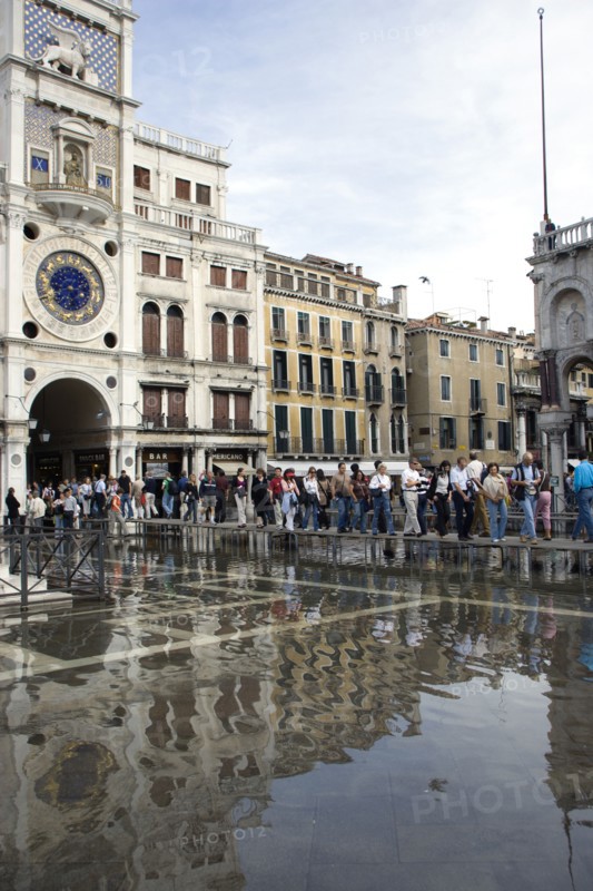 ITALY, Veneto, Venice, Aqua Alta High Water flooding in St Marks Square with tourists on elevated walkways above the flooded piazza beside St Marks Basilica and the Torre dell'Orologio clock tower