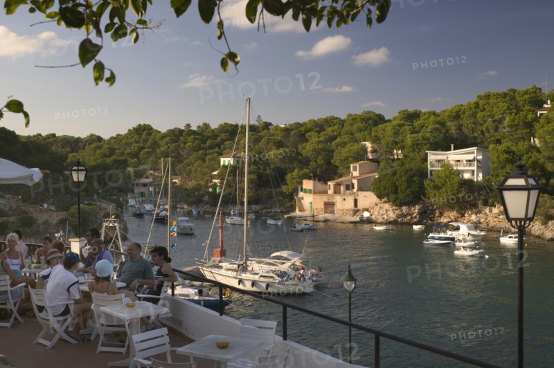 SPAIN, Balearic Islands, Mallorca, "Cala Figuera, Tourists enjoying a drink at a cafe over looking the harbour. "