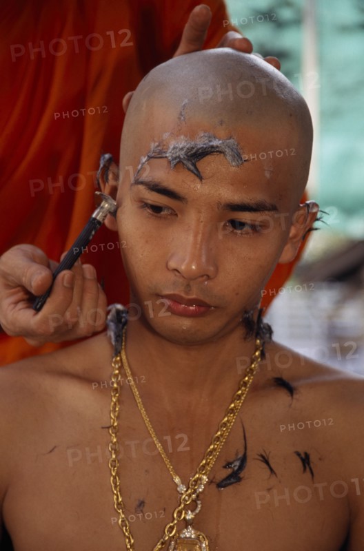 THAILAND, Bangkok, Novice monk having head shaved during ordination ceremony.