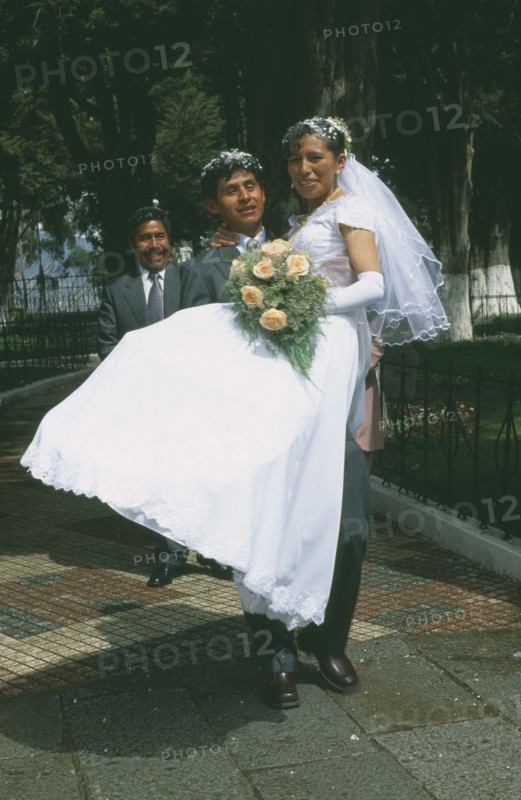 BOLIVIA, La Paz, Wedding in El Monticulo. Groom lifting up Bride.