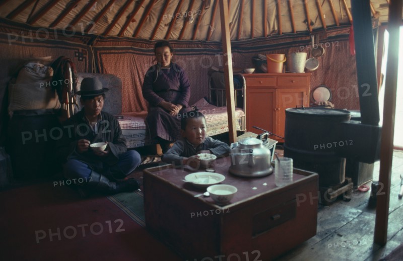 MONGOLIA, People, Family, Interior of yurt with family having meal in Summer.