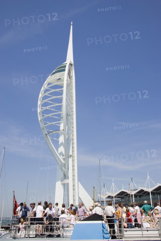 ENGLAND, Hampshire, Portsmouth, The Spinnaker Tower the tallest public viewing platforn in the UK at 170 metres on Gunwharf Quay with tourists on the deck of a harbour tour boat in the foreground