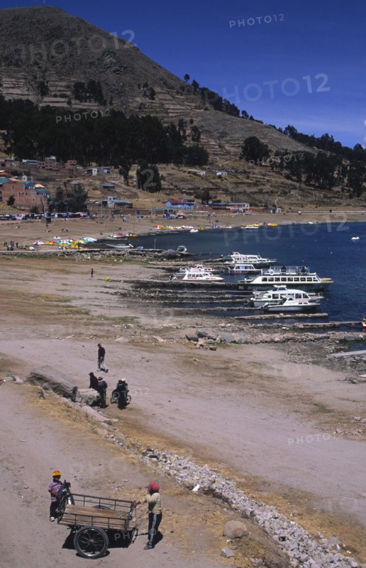 PERU, Puno, Lake Titicaca, Lake side scene with boats and people.