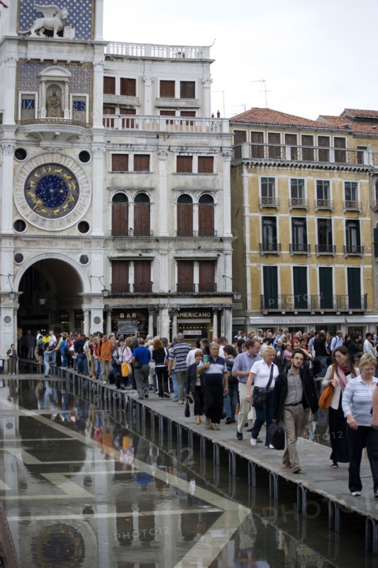 ITALY, Veneto, Venice, Aqua Alta High Water flooding in St Marks Square with tourists walking on elevated walkways beneath the Torre dell'Orologio clock tower Paul Seheult