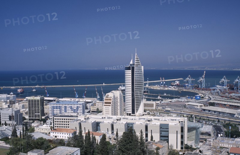 ISRAEL, Haifa, Elevated view of downtown area with modern tall buildings including a fish shaped skyscraper towards the docks and coastline in the background