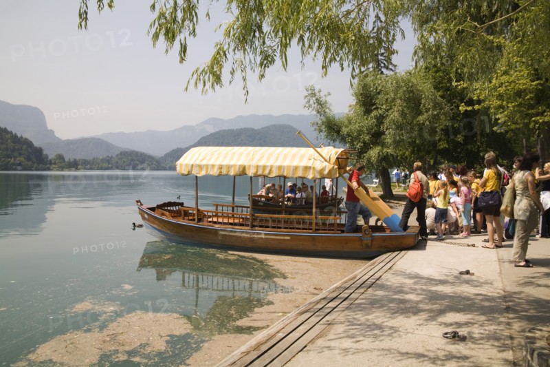 SLOVENIA, Lake Bled, Tourists queuing to board one of the rowing boats for a trip to the island and church - the second boat has just arrived back