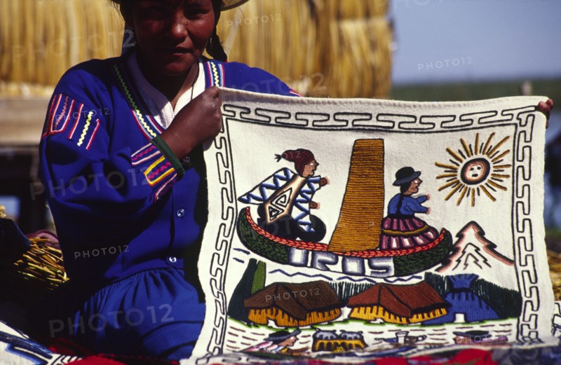 PERU, Puno Administrative Department, Lake Titicaca, "Uros floating islands/Aymara woman. The Aymara women who inhabit the floating reed islands of Uros on Lake Titicaca, make a living from tourism: selling hand made trinkets and patterned wall hangings"