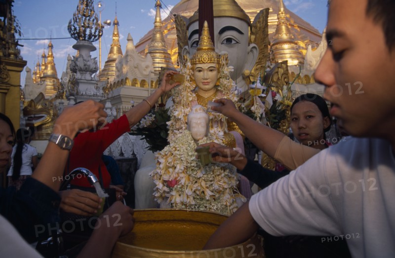 MYANMAR, Yangon, People making offerings of flowers and water at shrine in Shwedagon Pagoda.