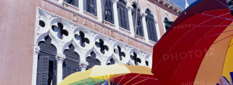 ITALY, Veneto, Venice, Facade of Danilei Hotel with coloured umbrellas on sale at street stall in the foreground.