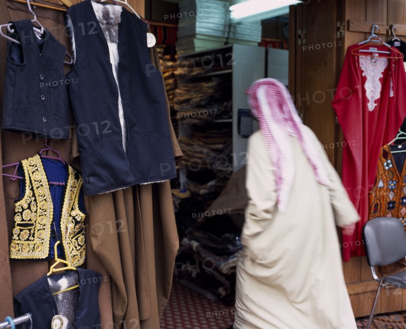 KUWAIT, Kuwait City, Man in Dishdasha and red and white shmaaq entering clothes shop in the Great Souq in blurred movement.
