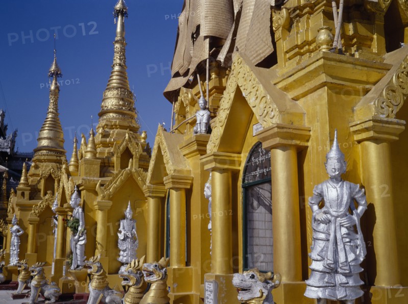 MYANMAR, Yangon, Shwedagon Paya.  Golden shrines and statues in temple complex.