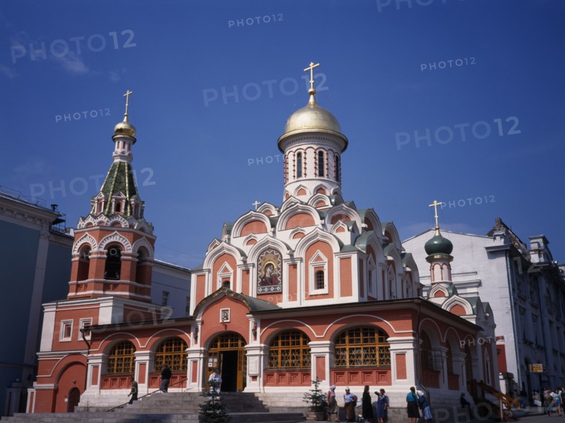 RUSSIA, Moscow, "Exterior of refurbished church with red and white painted facade, gold domed roof and painted icons above the entrance."