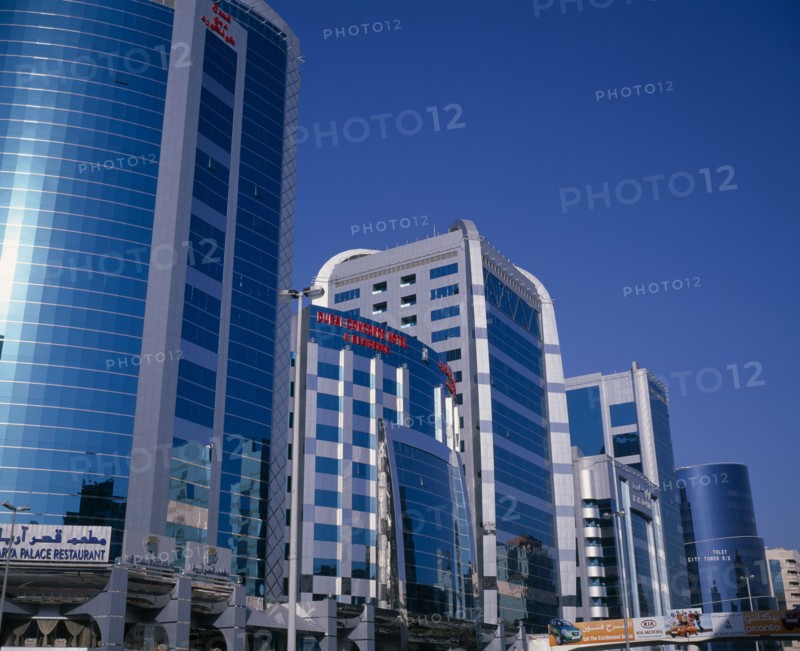 UAE, Dubai, Dubai Concorde Hotel and Residence on Al Maktoum Road.  Modern glass fronted exterior of hotel beside offices or apartments to let and advertising hoarding.