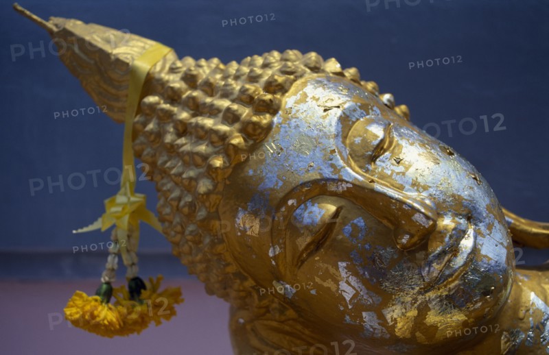 THAILAND, Koh Samui, Bophut, Head of reclining Buddha with gold leaf and floral offering.