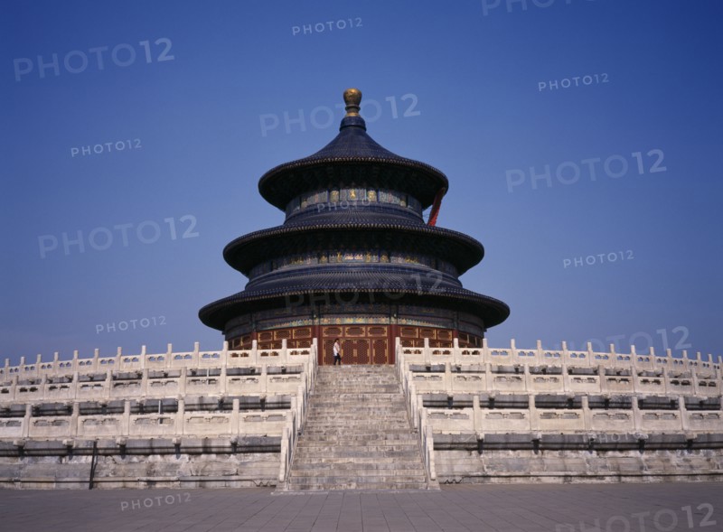 CHINA, Beijing, Temple of Heaven.  Hall of Prayer for Good Harvests with western tourist standing at top of steps to entrance.