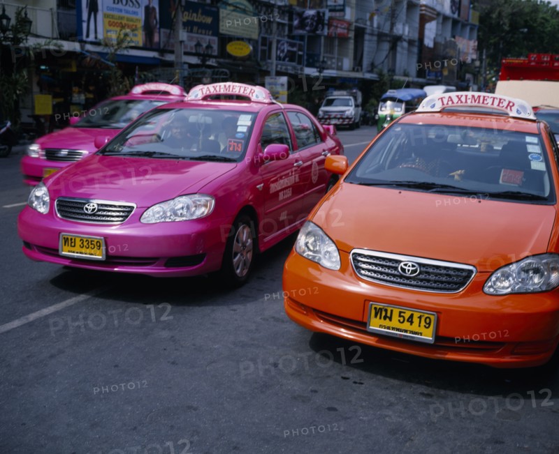 THAILAND, Bangkok, Pink and orange taxi cabs on busy road.