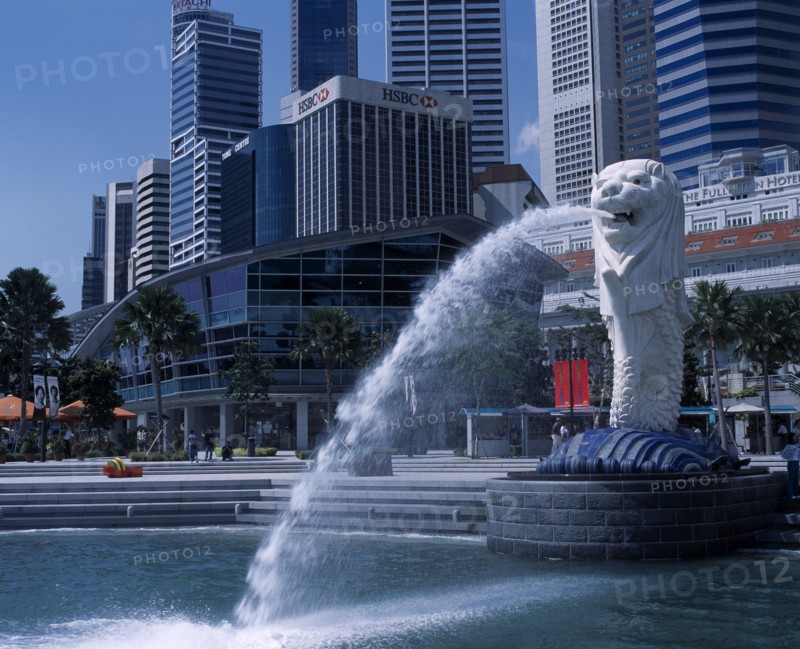 SINGAPORE, Merlion Park, Merlion statue and fountain in front of the Fullerton Hotel and city buildings including HSBC Bank and Tung Centre.