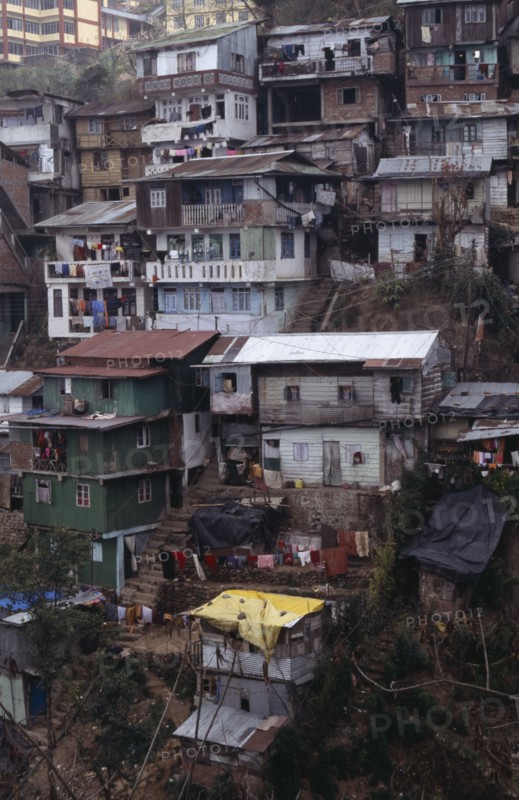 INDIA, West Bengal, Darjeeling, Poor quality housing on steep hillside strewn with litter.