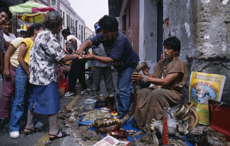 PERU, Lima, "Shaman selling snake grease and other ‘cures’ for ailments on city street with stall laid out with snake skins, reptile parts etc."