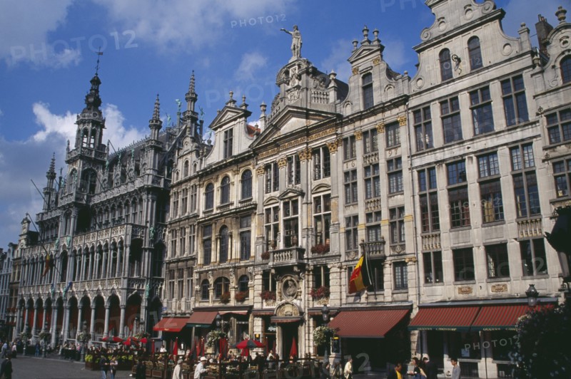 BELGIUM, Brabant, Brussels, Grand Place.  Maison du Roi on left beside decorative facades of old town buildings  busy outside tables of cafe and people crossing square. UNESCO World Heritage Site