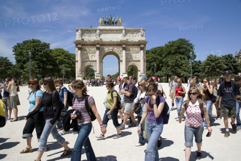 FRANCE, Ile de France, Paris, Students walking past the 19th Century Arc de Triomphe du Carrousel at the entrance to the Tuileries gardens beside the Louvre Museum