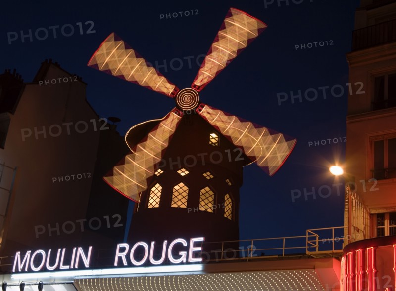 FRANCE, Ile de France, Paris, Montmartre The Moulin Rouge nightclub illuminated at night with the windmill sails rotating