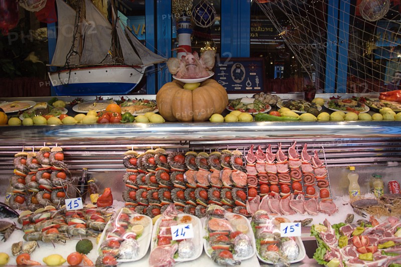 FRANCE, Ile de France, Paris, Greek restaurant window display in the Latin Quarter showing seafood and meat kebabs with a pigs head on a plate
