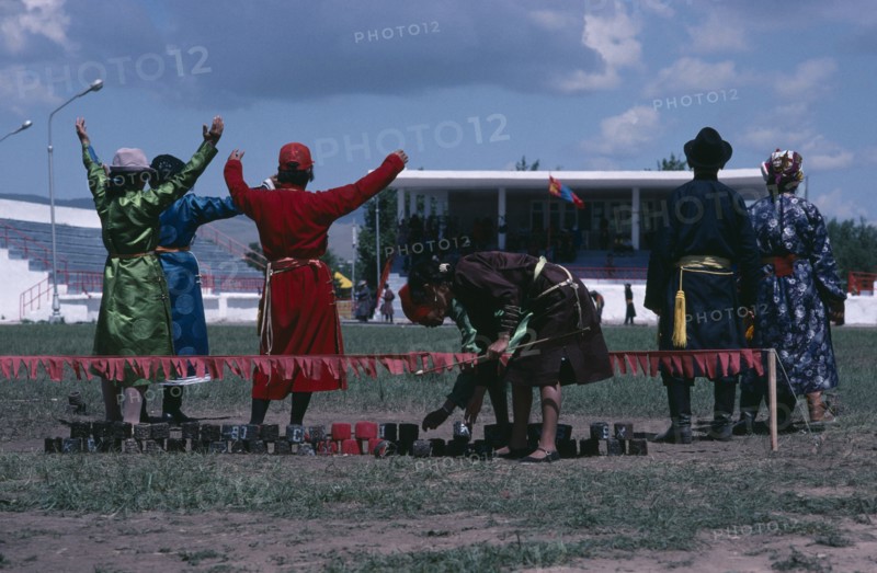 MONGOLIA, Sport, National Day archery contest.  Target line with red marking the bullseye and scorers signalling to competitors.
