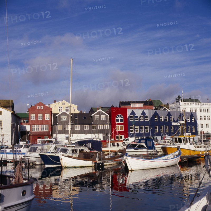 DENMARK, Faroe Islands, Torshavn, Boats moored in harbour with colourful waterfront buildings behind.