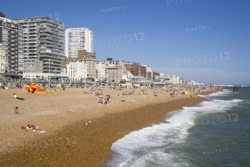 ENGLAND, East Sussex, Brighton, The beach with seafront apartment building behind.