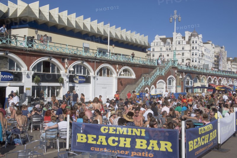 ENGLAND, East Sussex, Brighton, People sat outside the Beach Bar on the seafront.