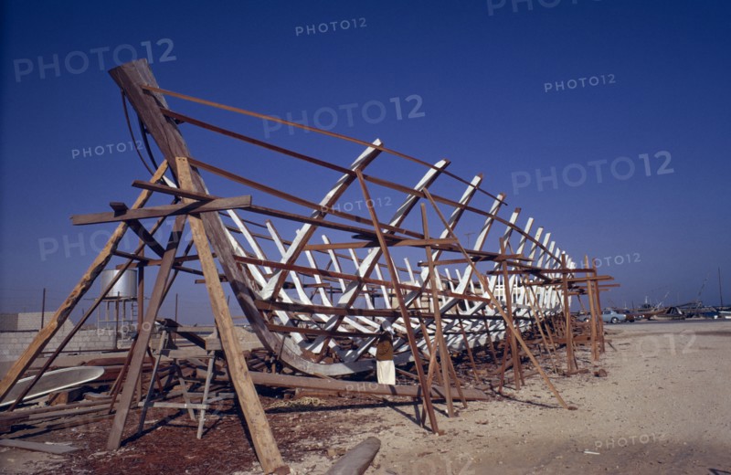 QATAR, Industry, Traditional dhow boat building.  Man standing below wooden frame.