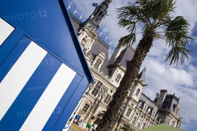 FRANCE, Ile de France, Paris, The Paris Plage urban beach. Young people playing beach volleyball behind beach huts in front of the Hotel de Ville Town Hall