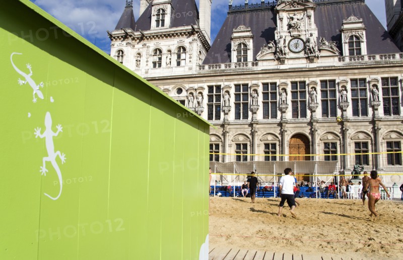 FRANCE, Ile de France, Paris, The Paris Plage urban beach. Young people playing beach volleyball behind a green beach hut with geckos painted on it in front of the Hotel de Ville Town Hall